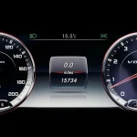 A compact sedan driving in daylight with the dashboard fuel economy display visible